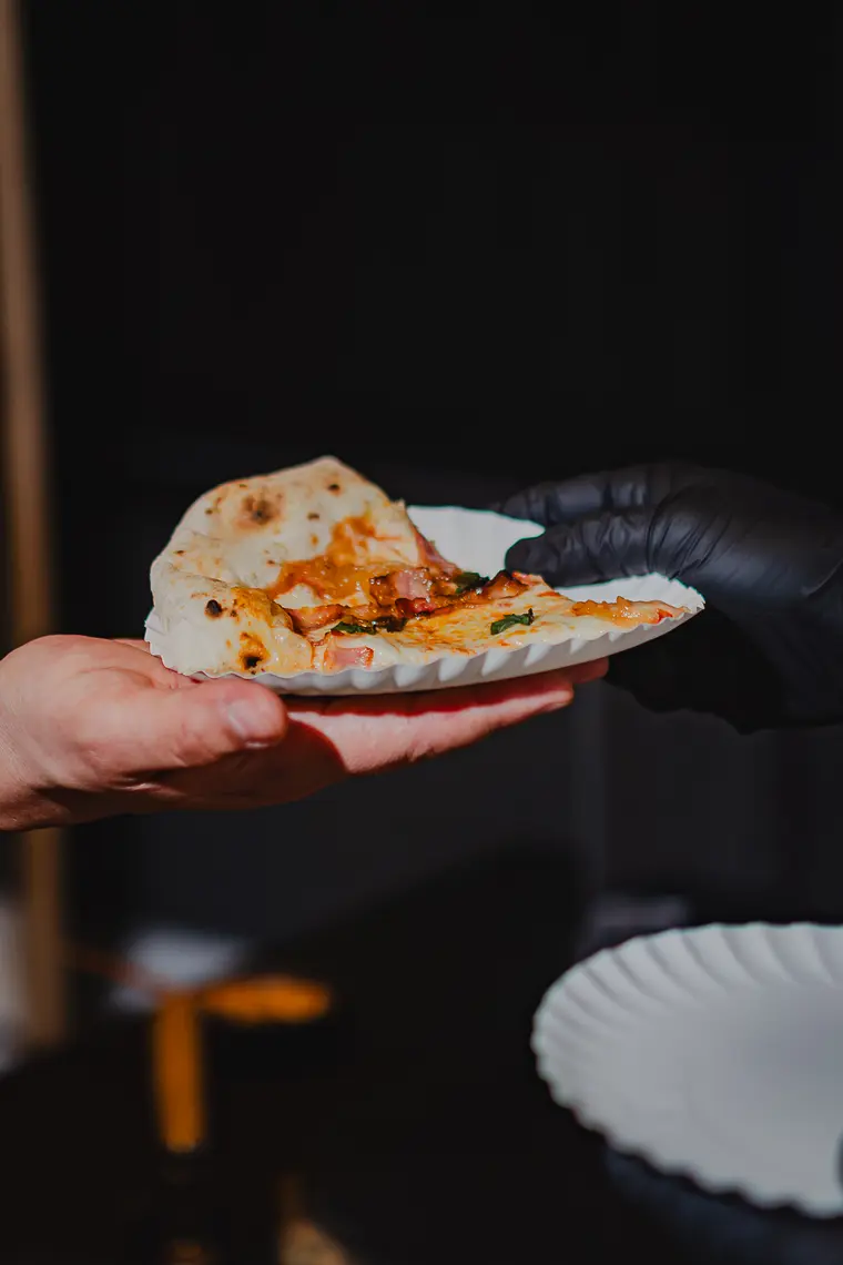 Porción de pizza entregada en mano