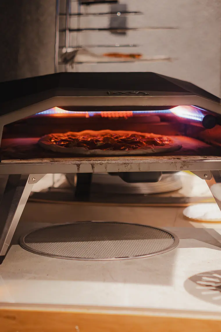 Pizza dentro del horno con la llama encendida
