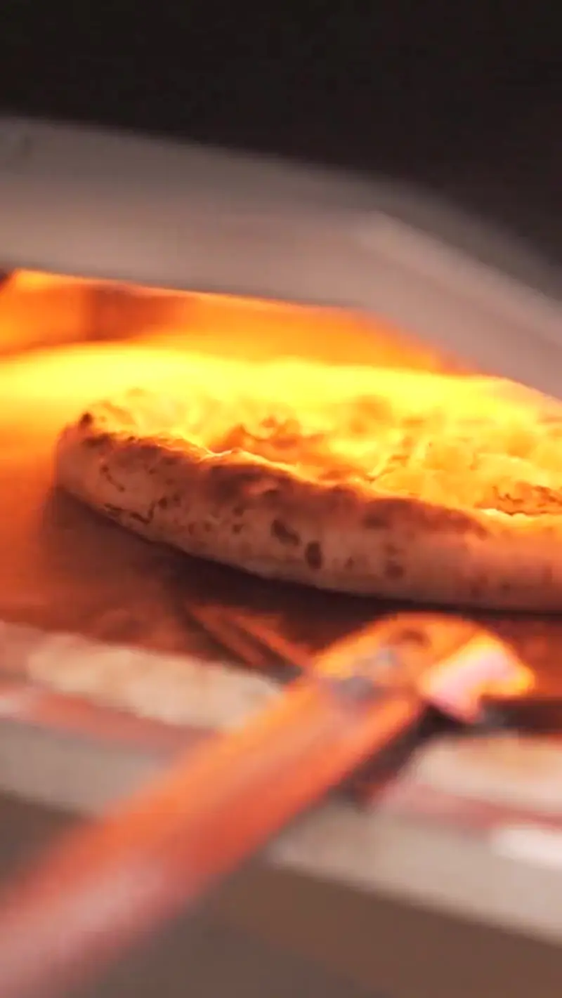 Pizza cociéndose en el horno entre las llamas
